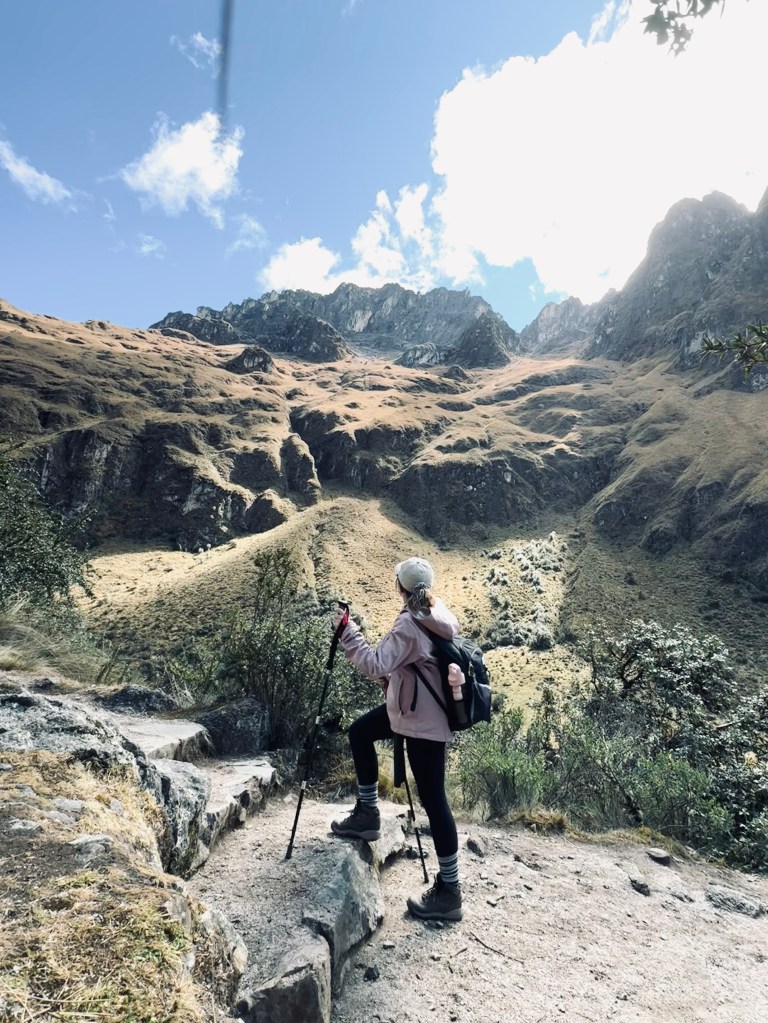 Girl trekking up stone steps looking at mountains on the Inca Trail in Peru