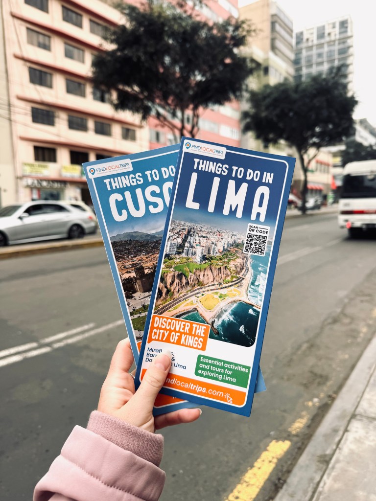 Hand holding Lima and Cusco tourist maps with city in background in Miraflores, Lima, Peru