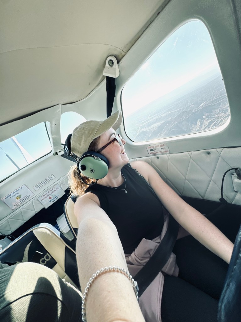Girl taking selfie looking out small plane window at mountains on a Nazca Lines flight tour in Nazca, Peru