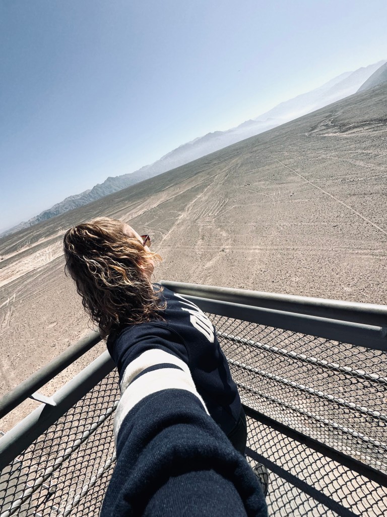 Girl taking selfie looking out at Nazca Lines from lookout tower in Nazca, Peru