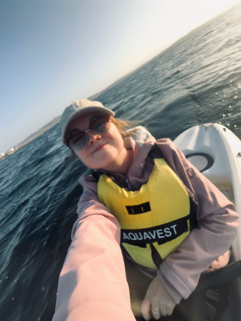 Girl in lifejacket taking selfie in a kayak at golden hour in Paracas, Peru