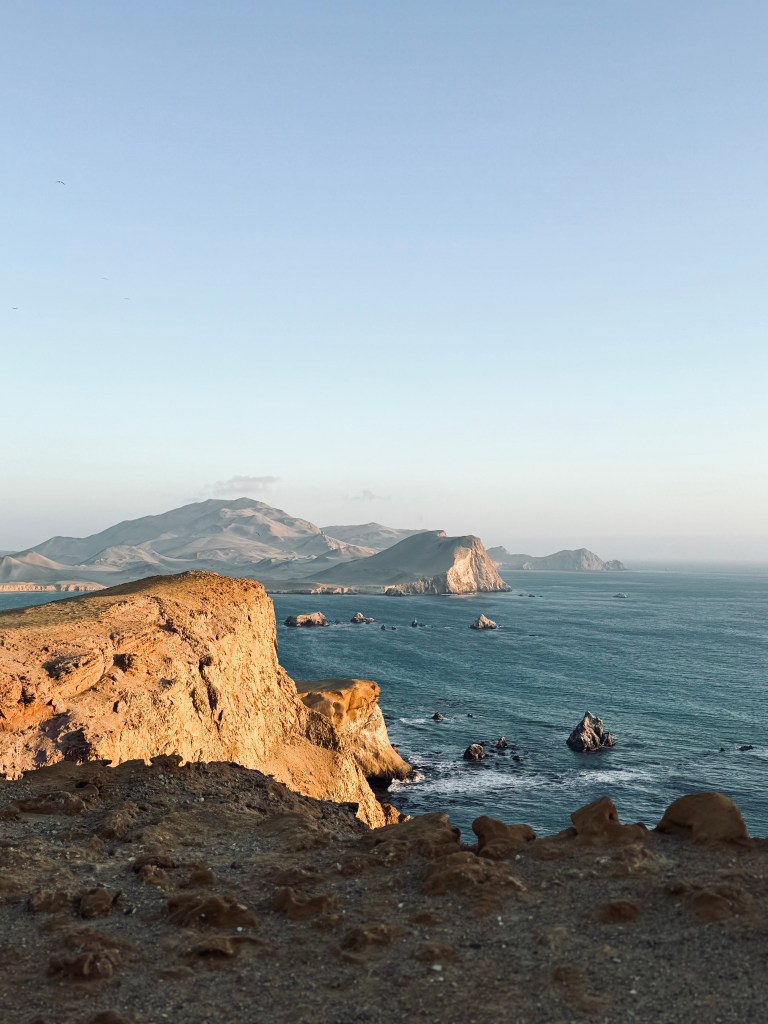 Golden hour over ocean and cliff formations in Paracas National Reserve, Peru