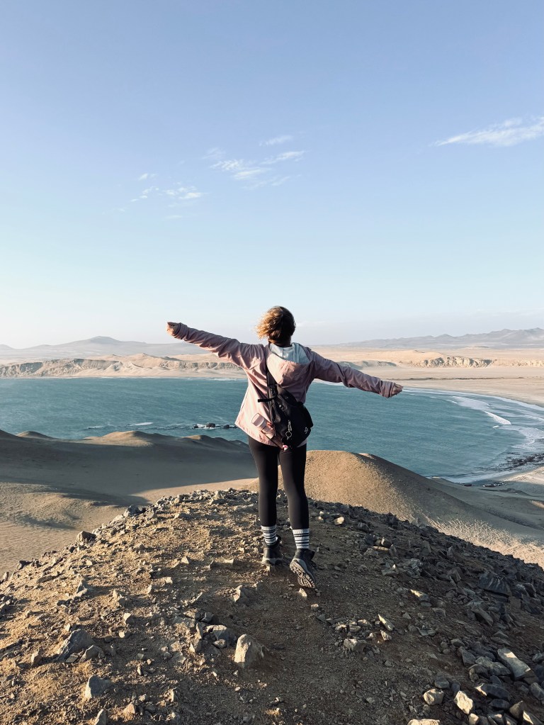 Girl looking out over ocean and desert at Paracas National Reserve, Peru