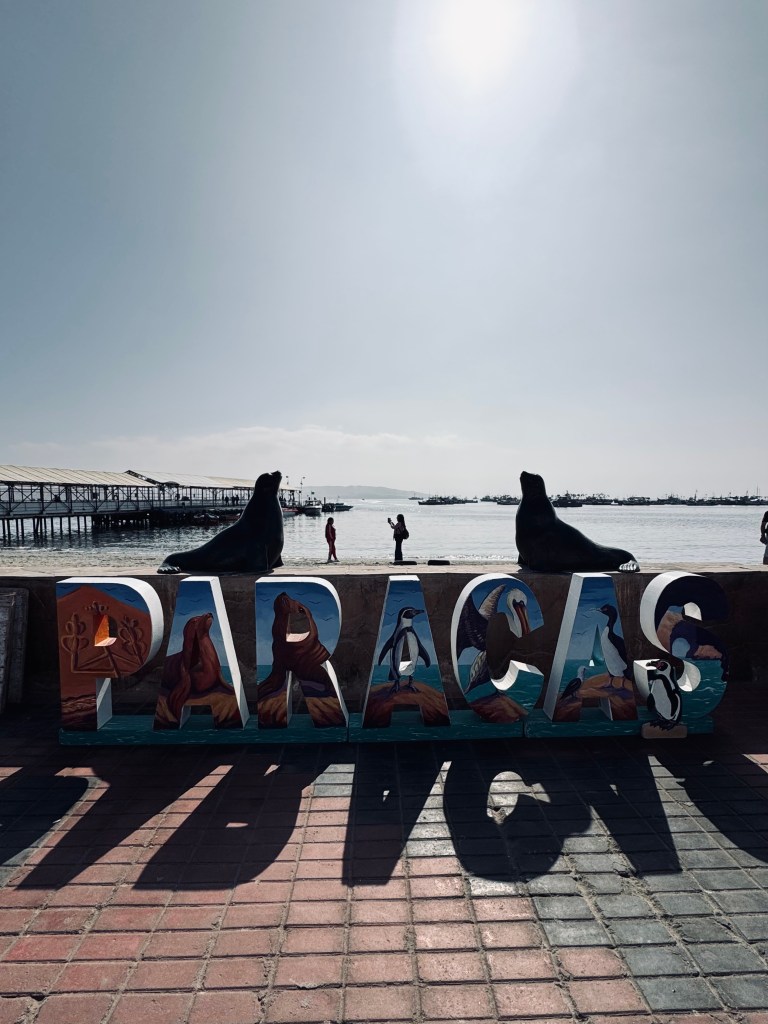 Paracas tourism sign with ocean in background in Paracas, Peru
