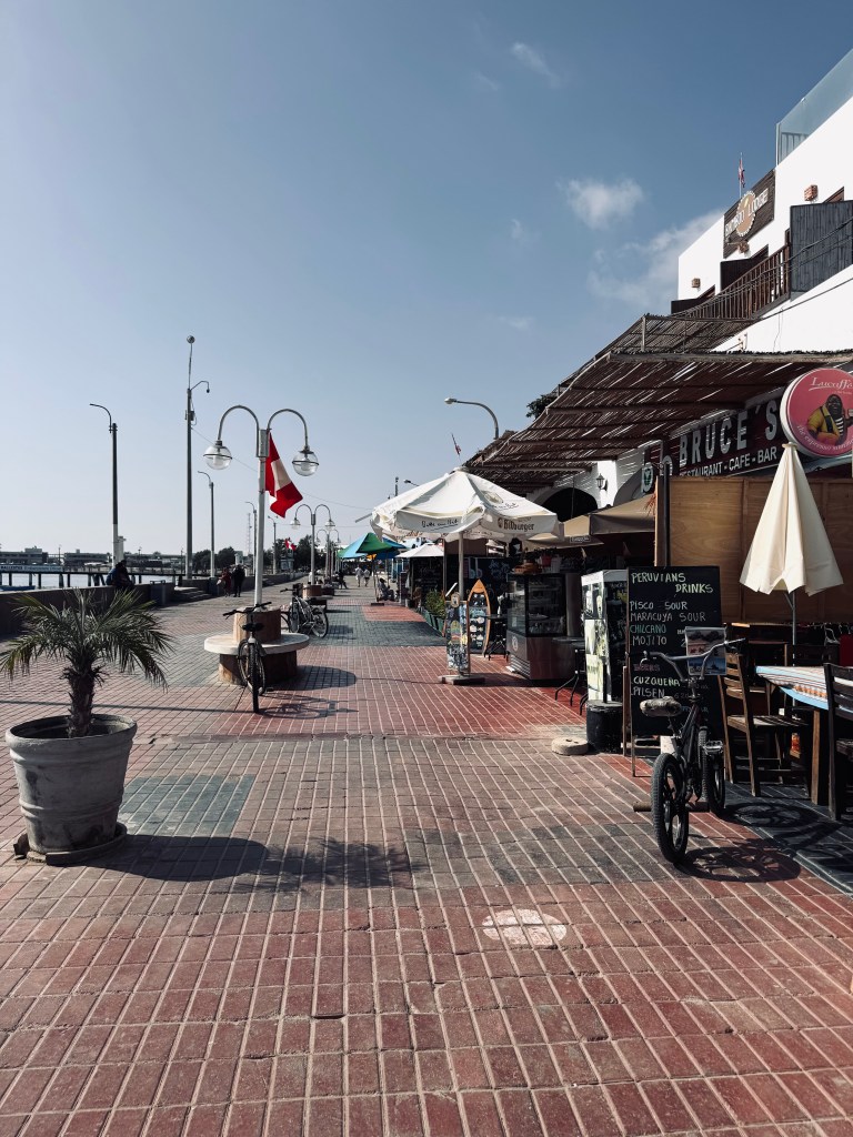 Promenade street with restaurants and Peru flag in Paracas, Peru