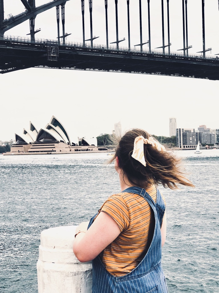 Girl looking out over Sydney Opera House and Sydney Harbour Bridge on a cloudy day in Australia