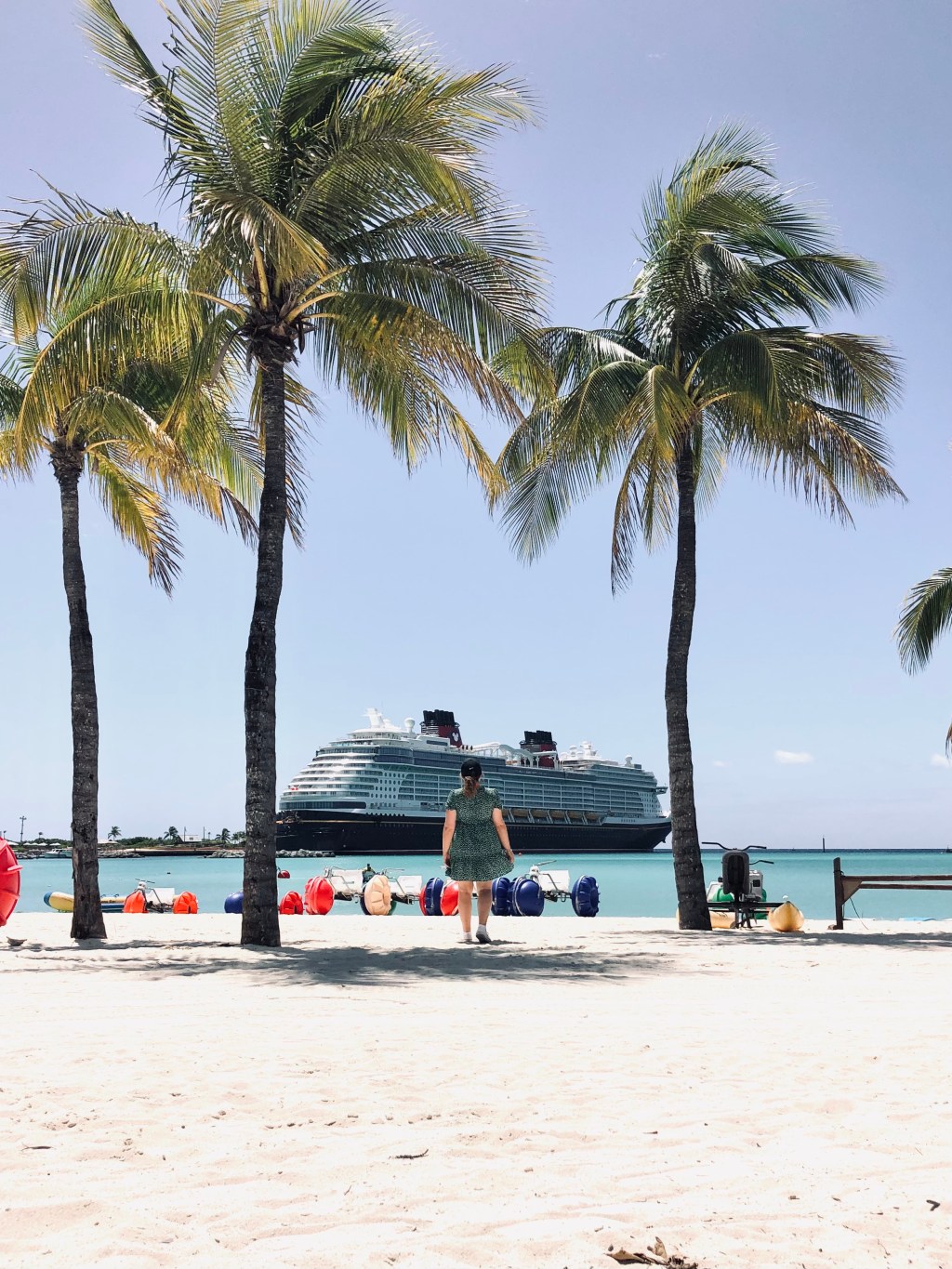 Beach with palm trees and Disney cruise ship docked in background at Castaway Cay, Bahamas