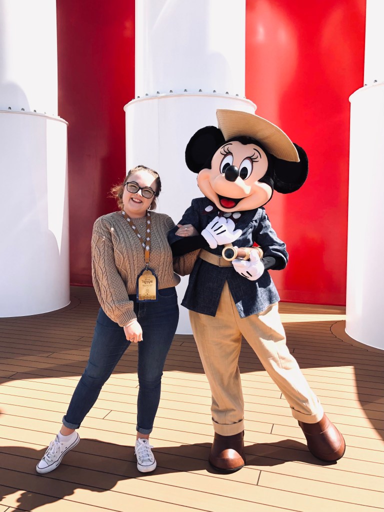 Girl posing with Minnie Mouse dressed up in a voyager outfit onboard a Disney Cruise Line cruise ship