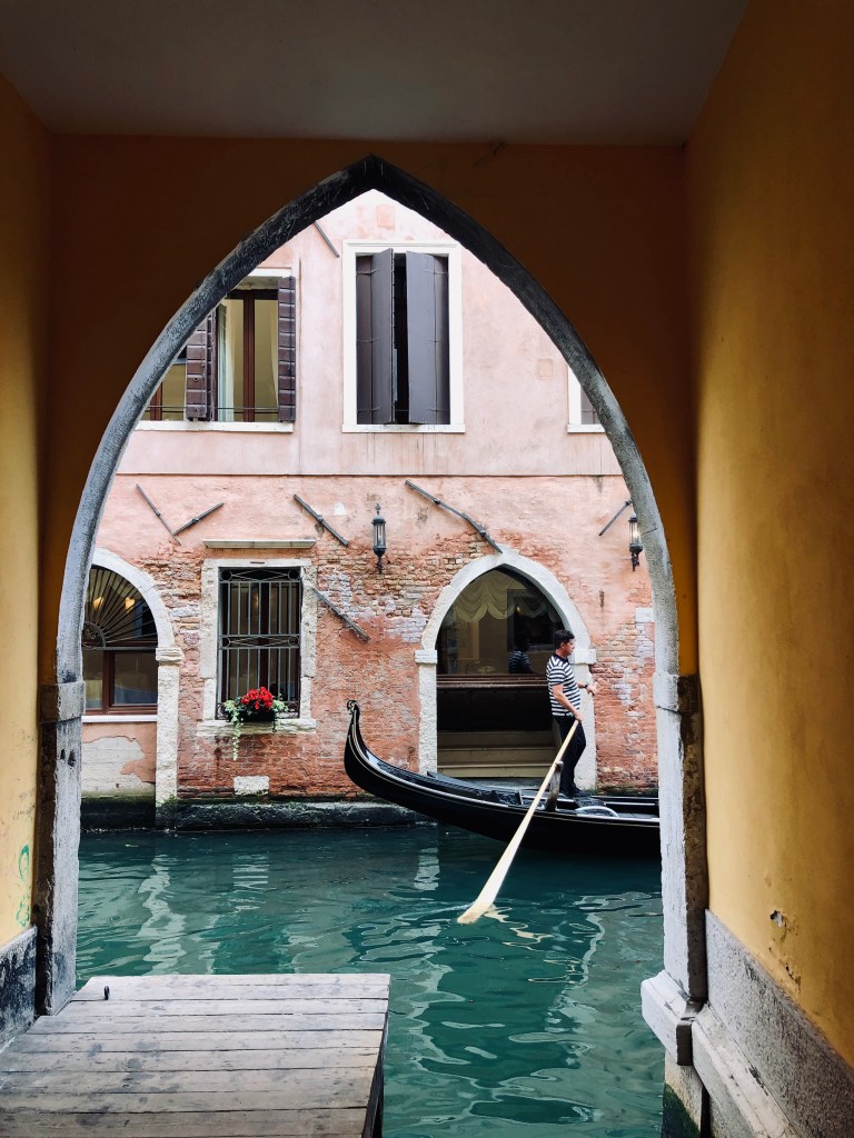 Gondola floating in the canals through an archway in Venice, Italy