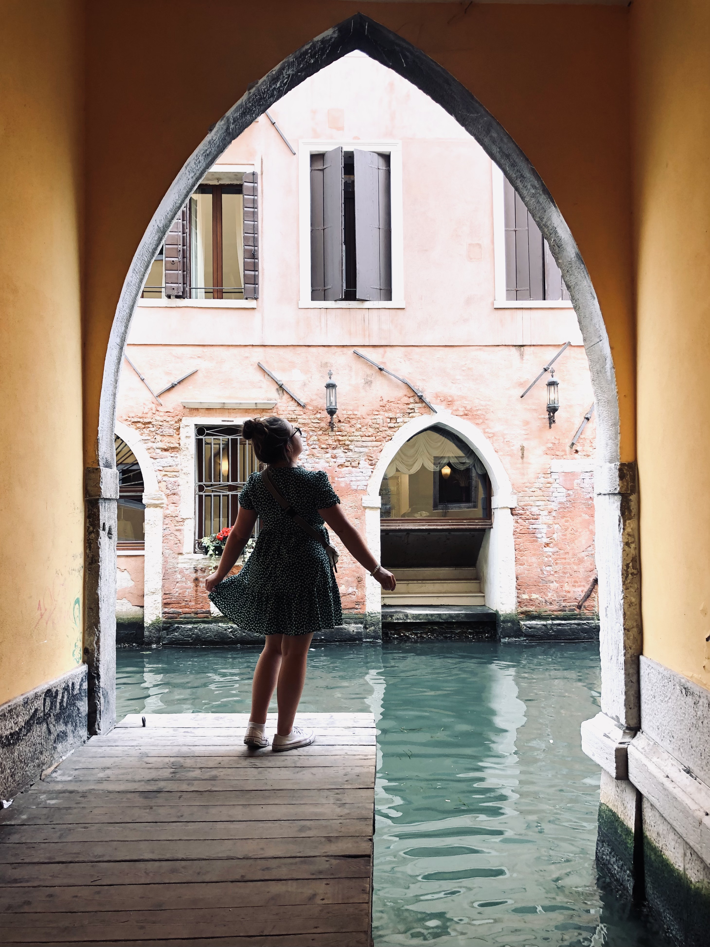 Girl looking out through an archway to the canals in Venice, Italy