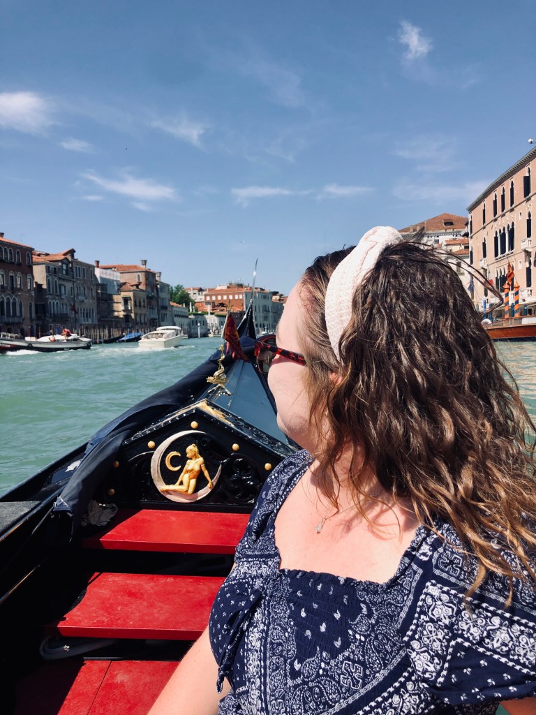 Girl sitting on a gondola on a sunny day in Venice, Italy