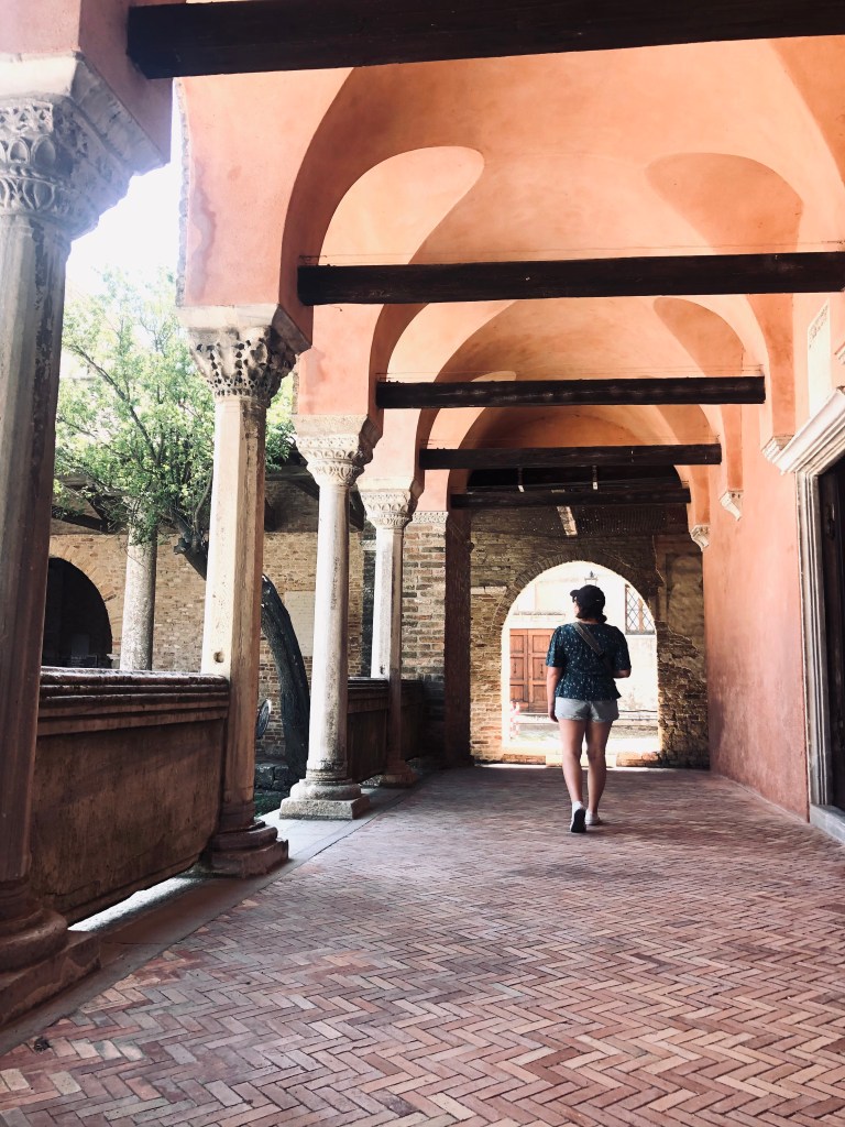 Girl walking under beautiful old archways on Torcello Island in Venice, Italy