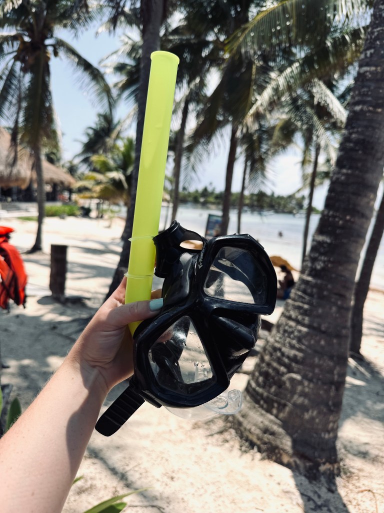 Hand holding snorkel mask at Akumal Beach in Mexico