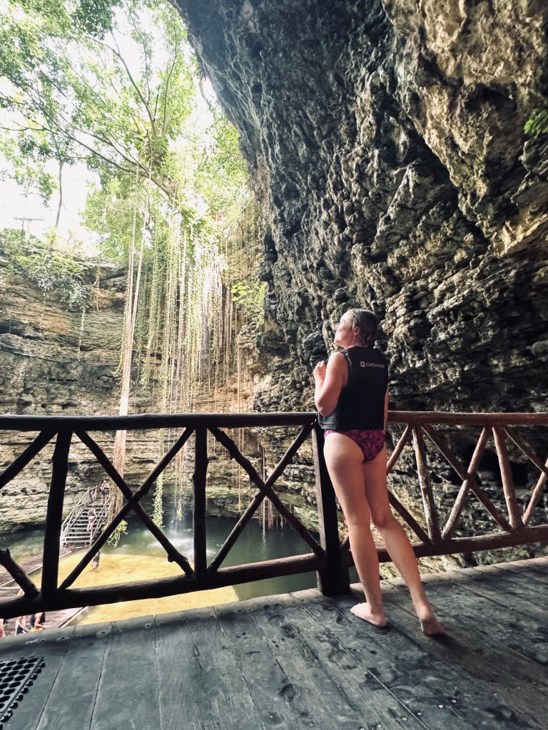 Girl in lifejacket looking up at Chichikan Cenote sinkhole in Mexico