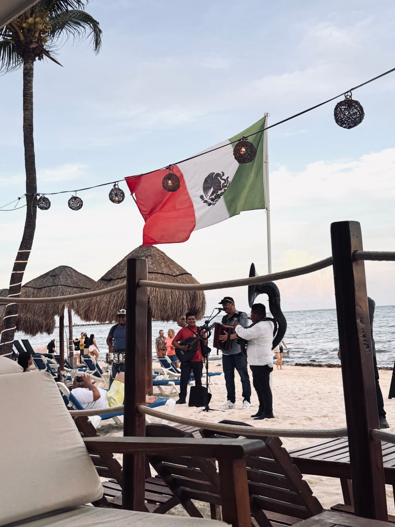 Musicians playing on beach under mexican flag at Playa del Carmen in Mexico