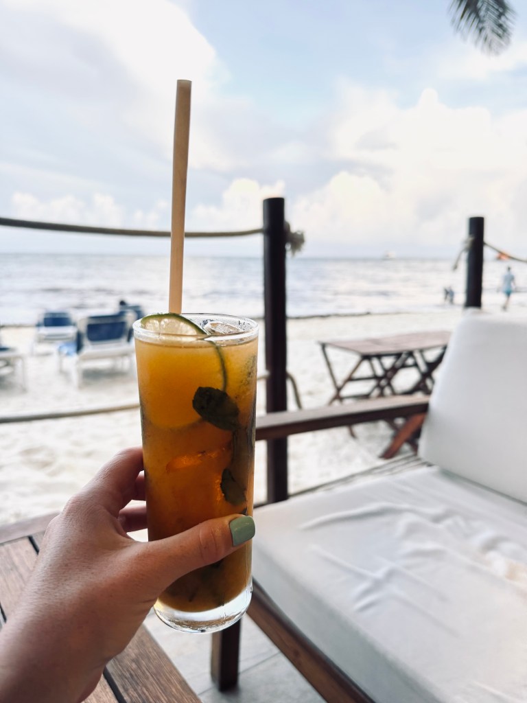 Hand holding mango mojito on the beach at Playa del Carmen in Mexico