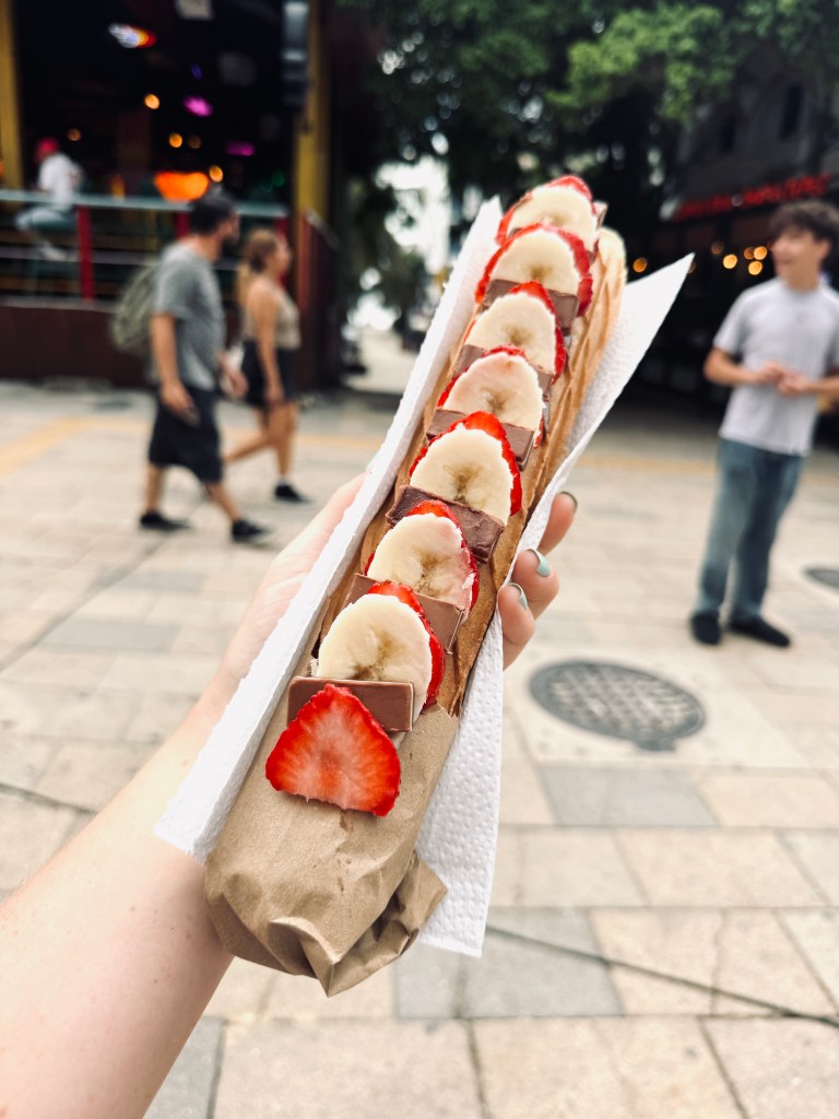 Hand holding marquesita waffle with strawberries and bananas at Playa del Carmen in Mexico