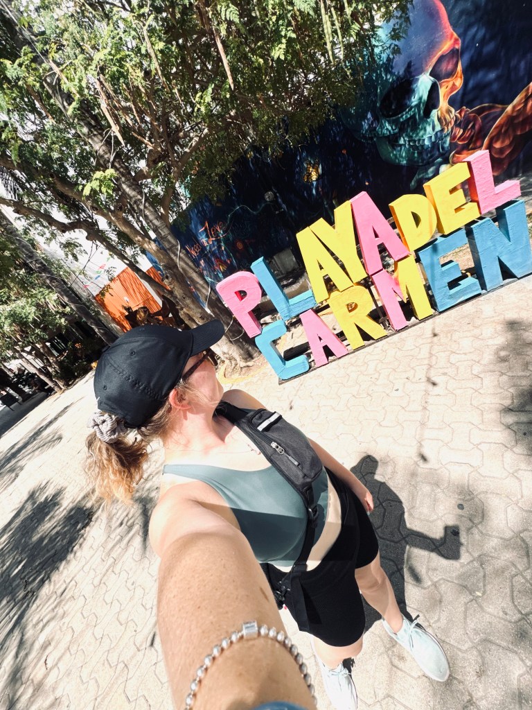 Girl taking selfie looking at tourist sign at Playa del Carmen in Mexico