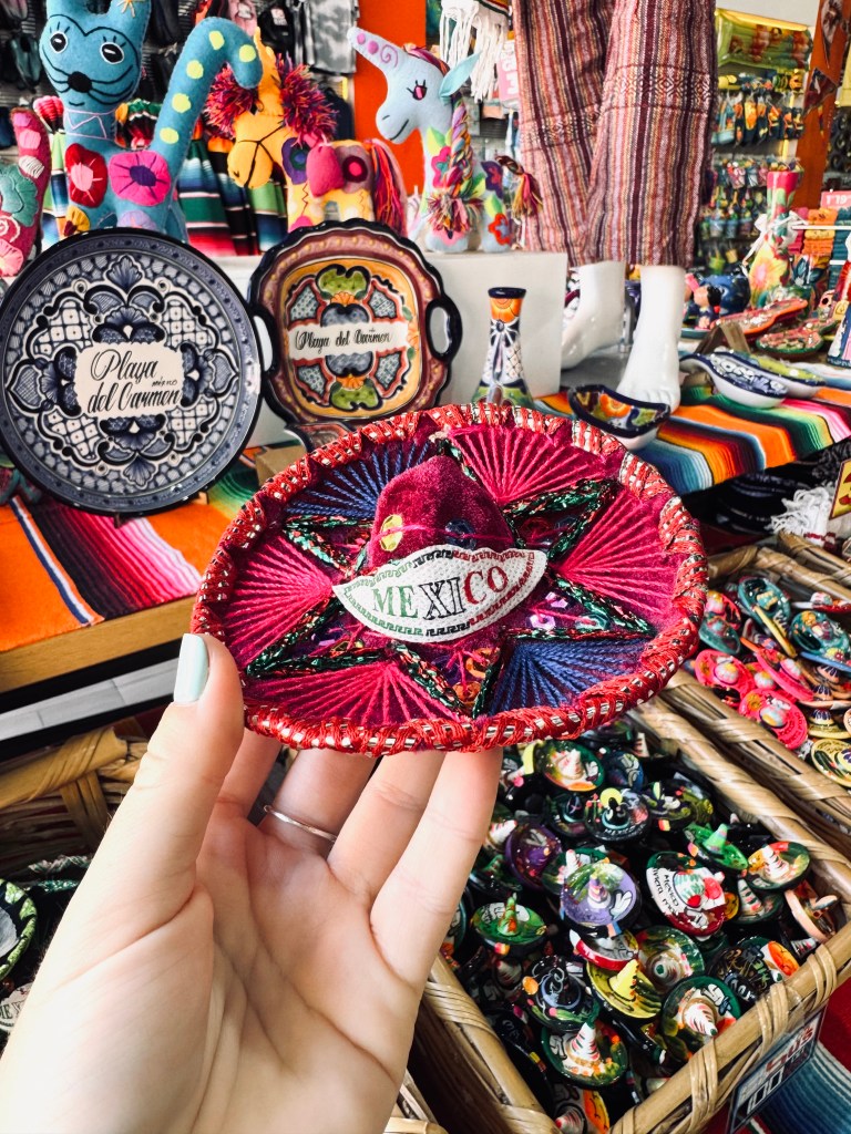 Hand holding small mexican sombrero souvenir at Playa del Carmen in Mexico