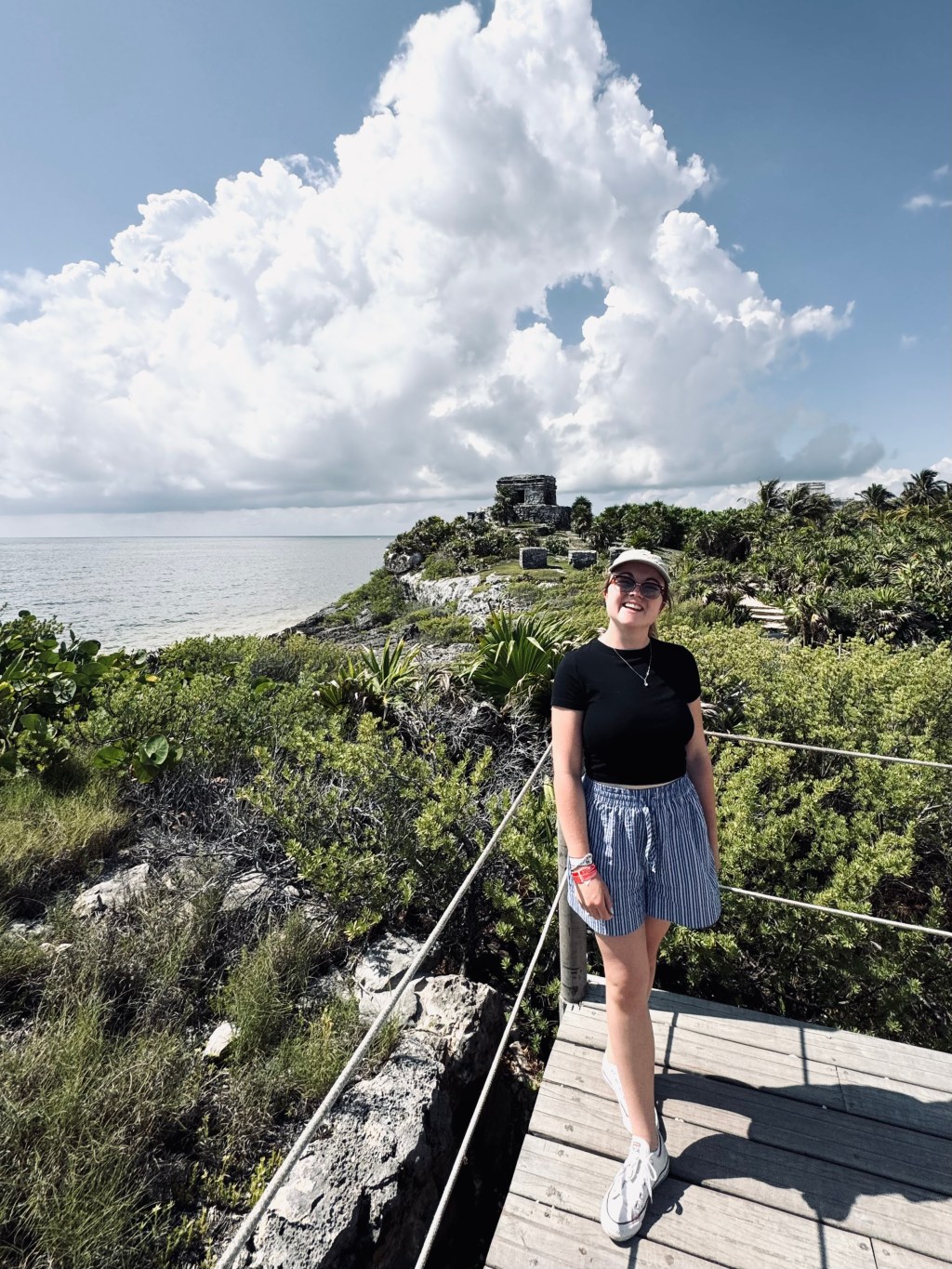 Girl smiling in front of ruins and beach at Tulum Ruins, Mexico