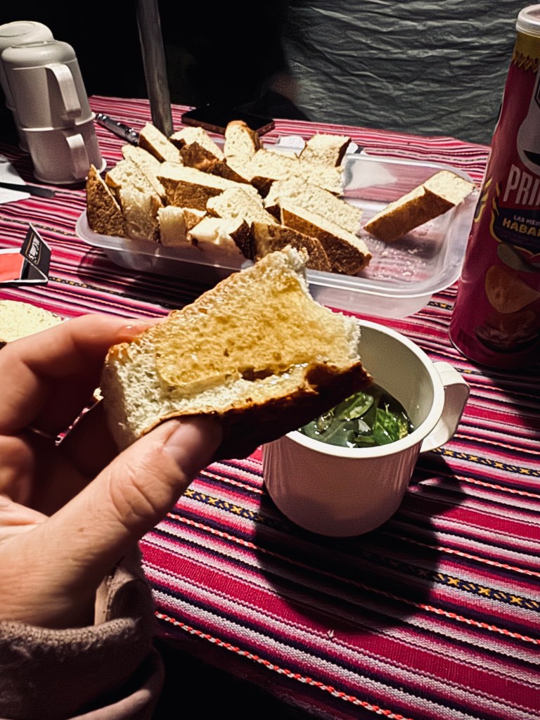 Hand holding bread with butter and coca tea in background on the Inca Trail, Peru