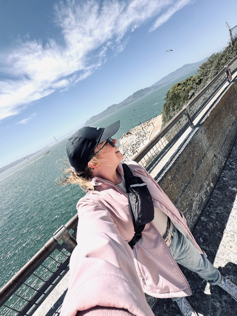Girl taking selfie with view of Golden Gate Bridge in background in San Fransisco, USA