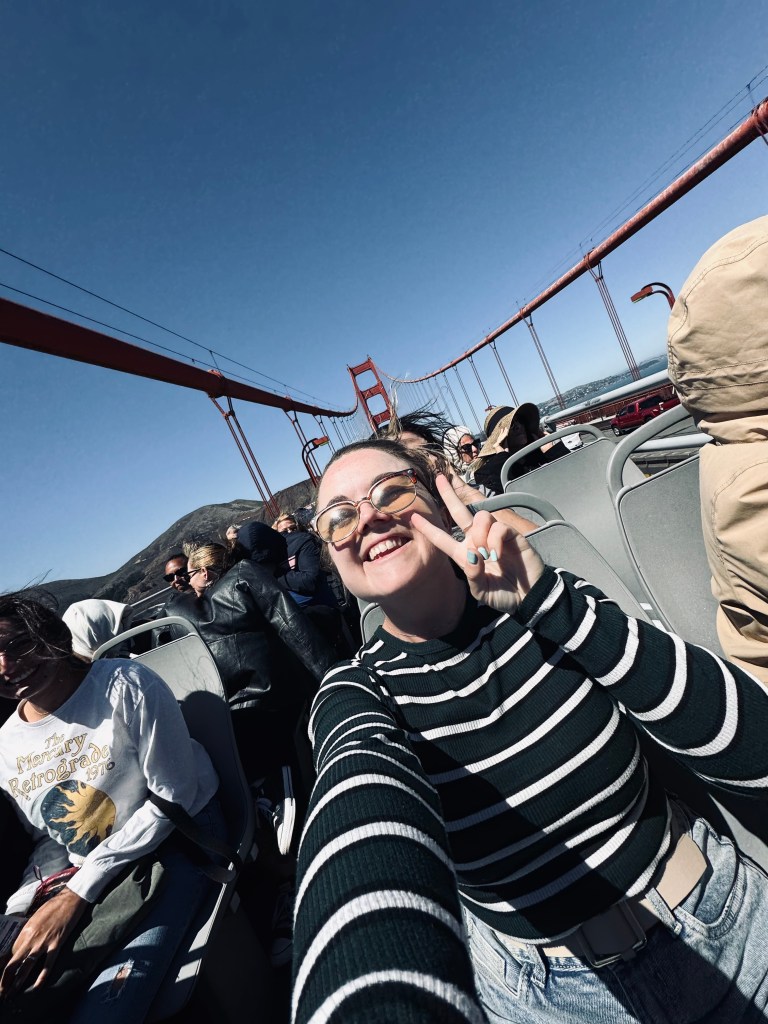 Girl taking selfie on a tour bus going across the Golden Gate Bridge on a sunny clear day in San Fransisco, USA