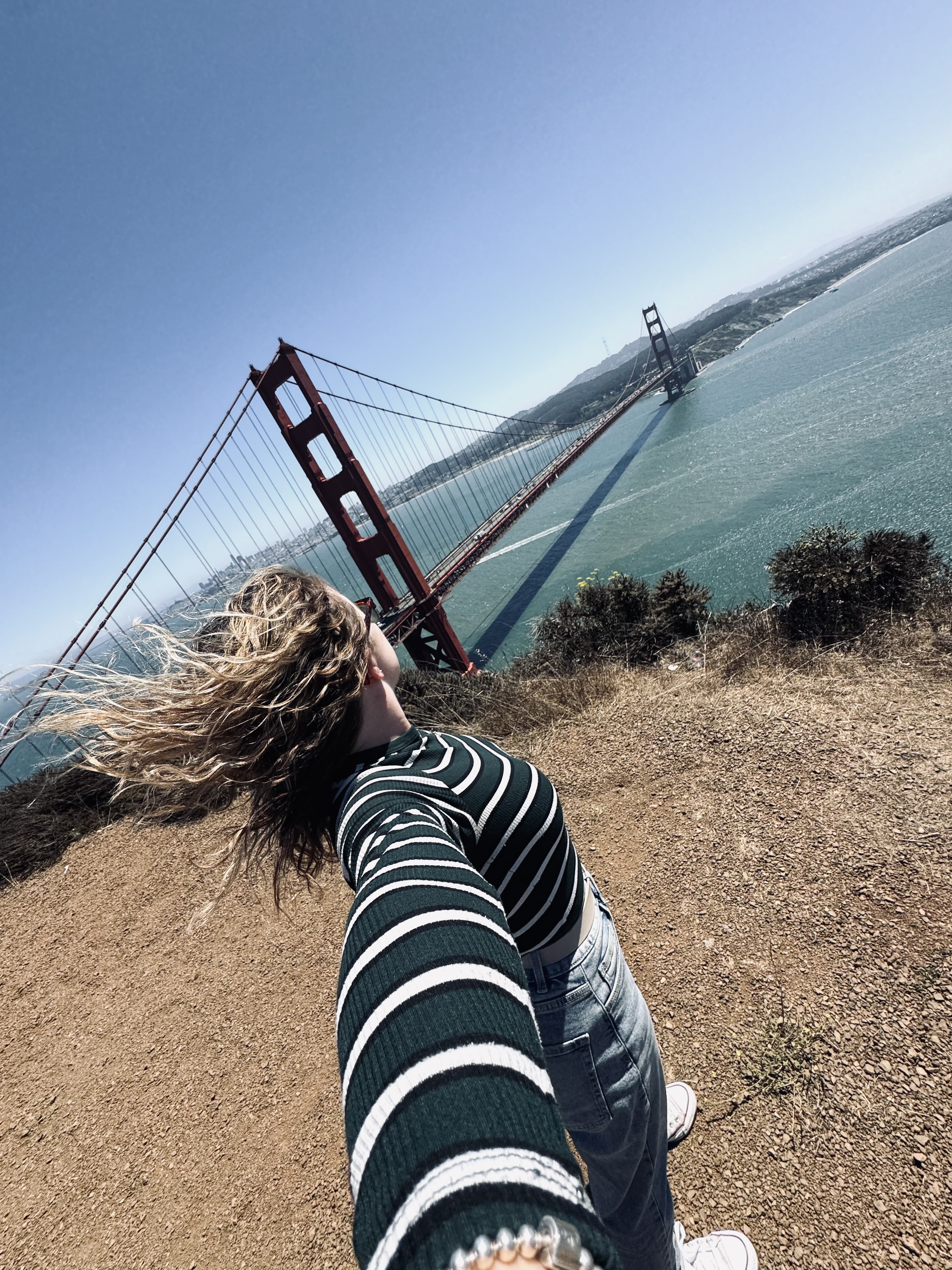 Girl taking selfie looking back at the Golden Gate Bridge on a sunny clear day in San Fransisco, USA
