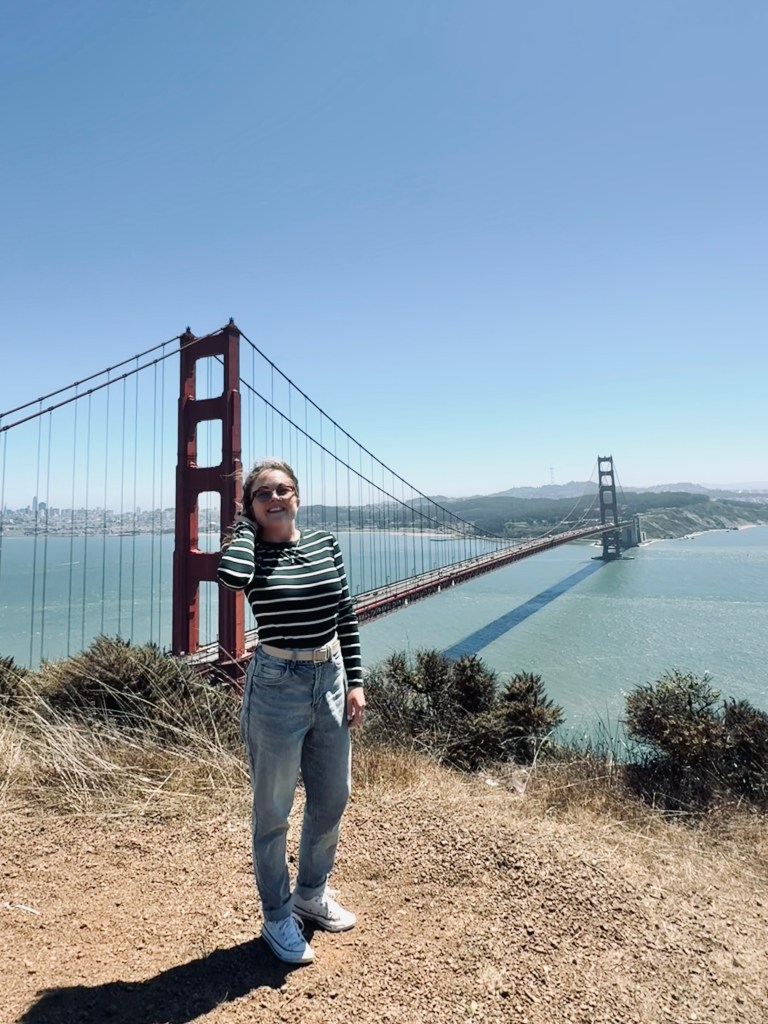 Girl standing in front of Golden Gate Bridge on a clear day in San Fransisco, USA