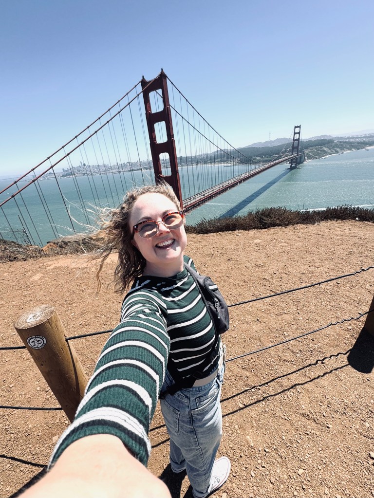 Girl taking selfie with Golden Gate Bridge on a clear day in San Fransisco, USA