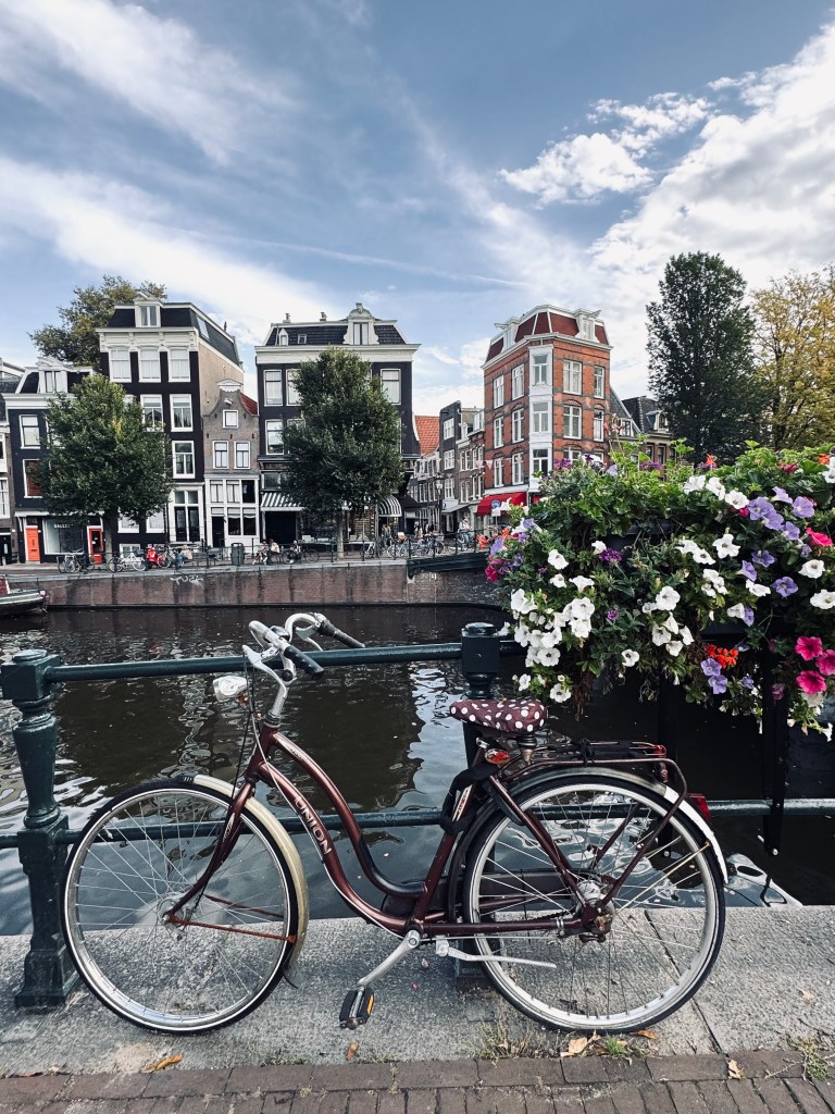 Cute bike leaning on a rail with canal and quaint buildings in the background in Amsterdam, The Netherlands