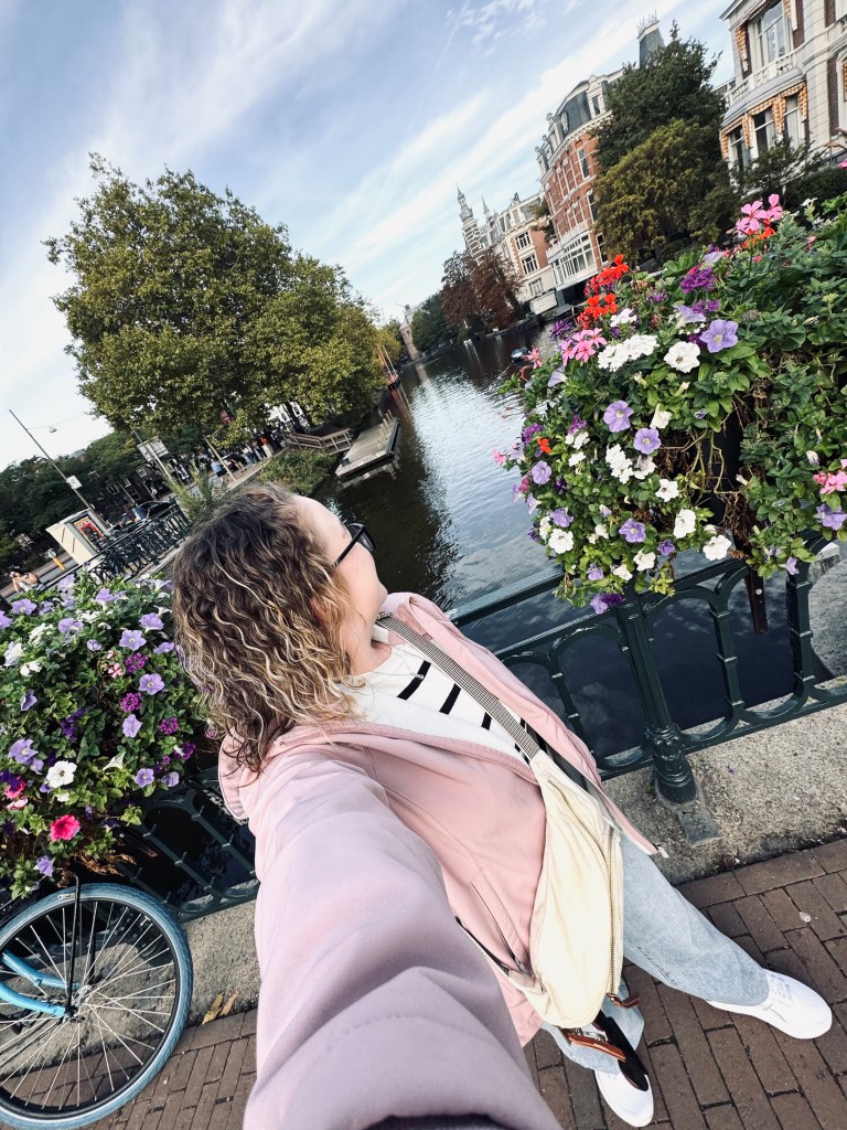 Girl taking selfie with canals and flowers in Amsterdam, The Netherlands