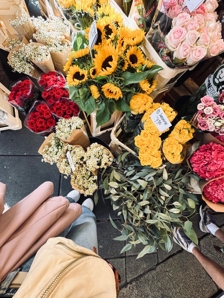 Feet and flowers in pots in a flower market stall in Amsterdam, The Netherlands
