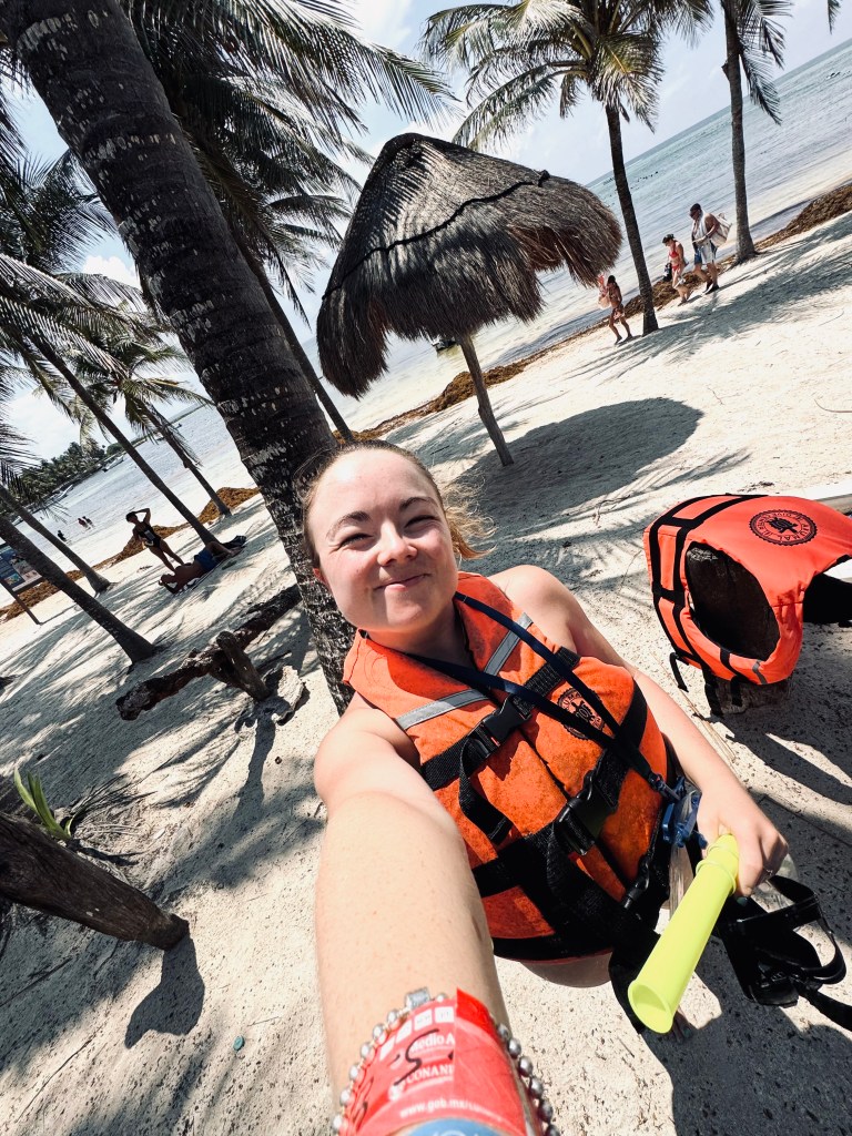 Girl in orange life jacket taking a selfie at Akumal Beach in Mexico