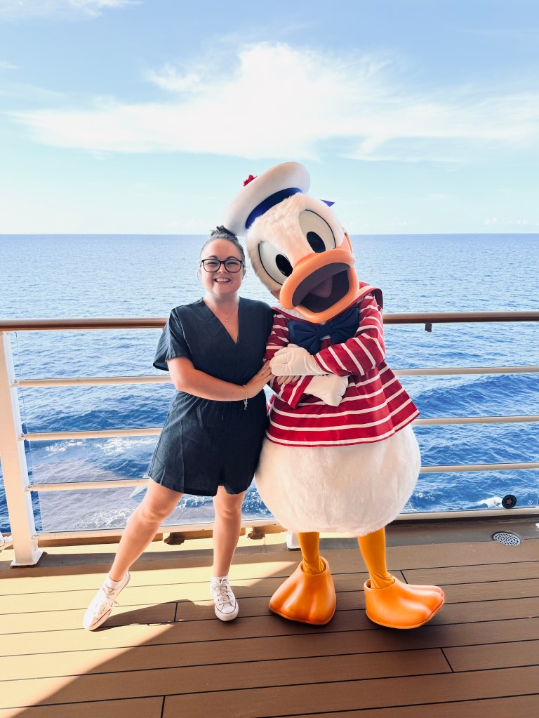 Girl smiling with Donald Duck onboard a disney cruise ship