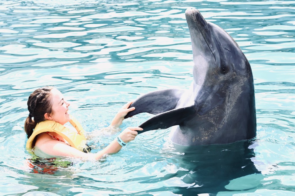 Girl holding dolphin fins while swimming with dolphins