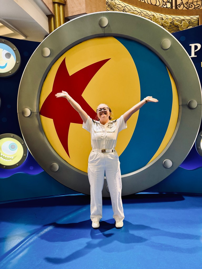 Disney cruise line officer smiling in front of pixar ball on pixar day at sea