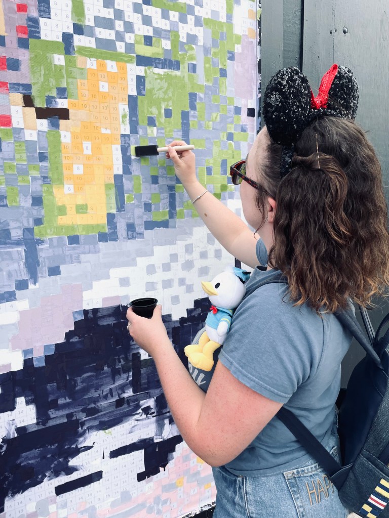 Girl painting on a paint by number mural at EPCOT