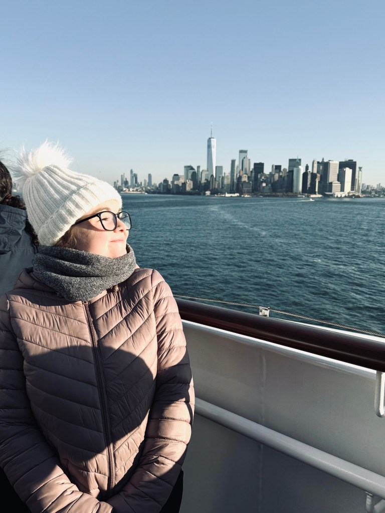 Girl in pink jacket looking out at skyline of NYC