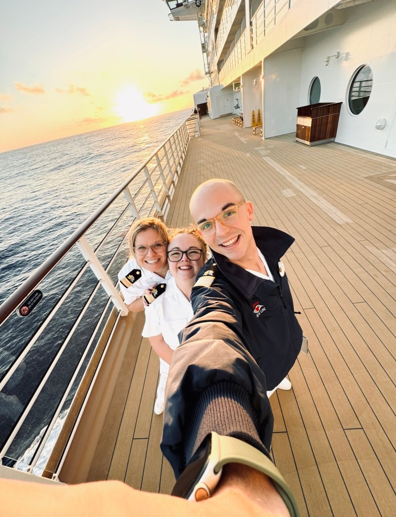 Disney Cruise Line crew members taking a selfie on deck at sunset