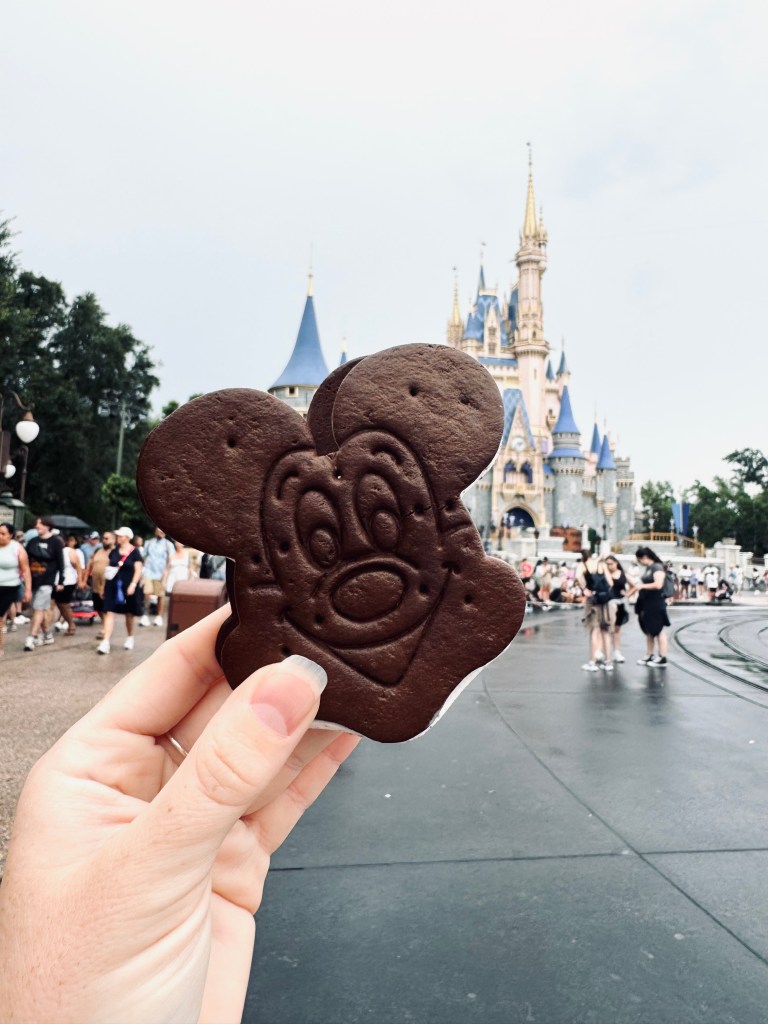 Hand holding Mickey Ice Cream Sandwich with castle in background at Magic Kingdom, Walt Disney World
