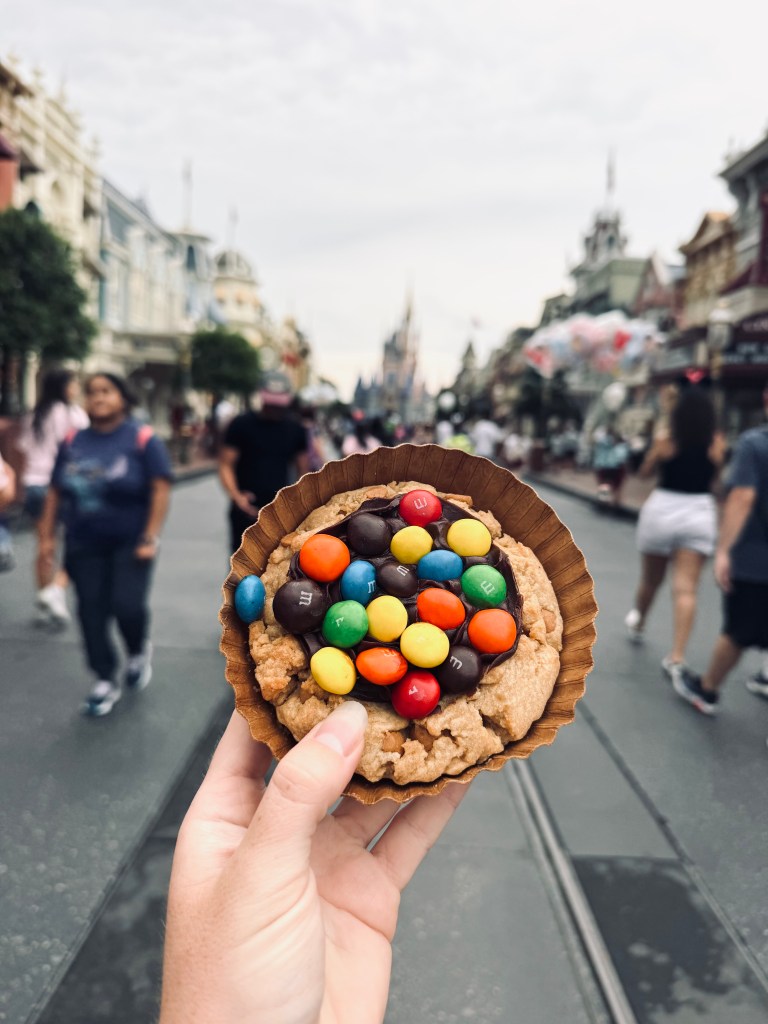 Hand holding peanut butter cookie pie with peanut m&ms at on Main Street USA at Magic Kingdom, Walt Disney World