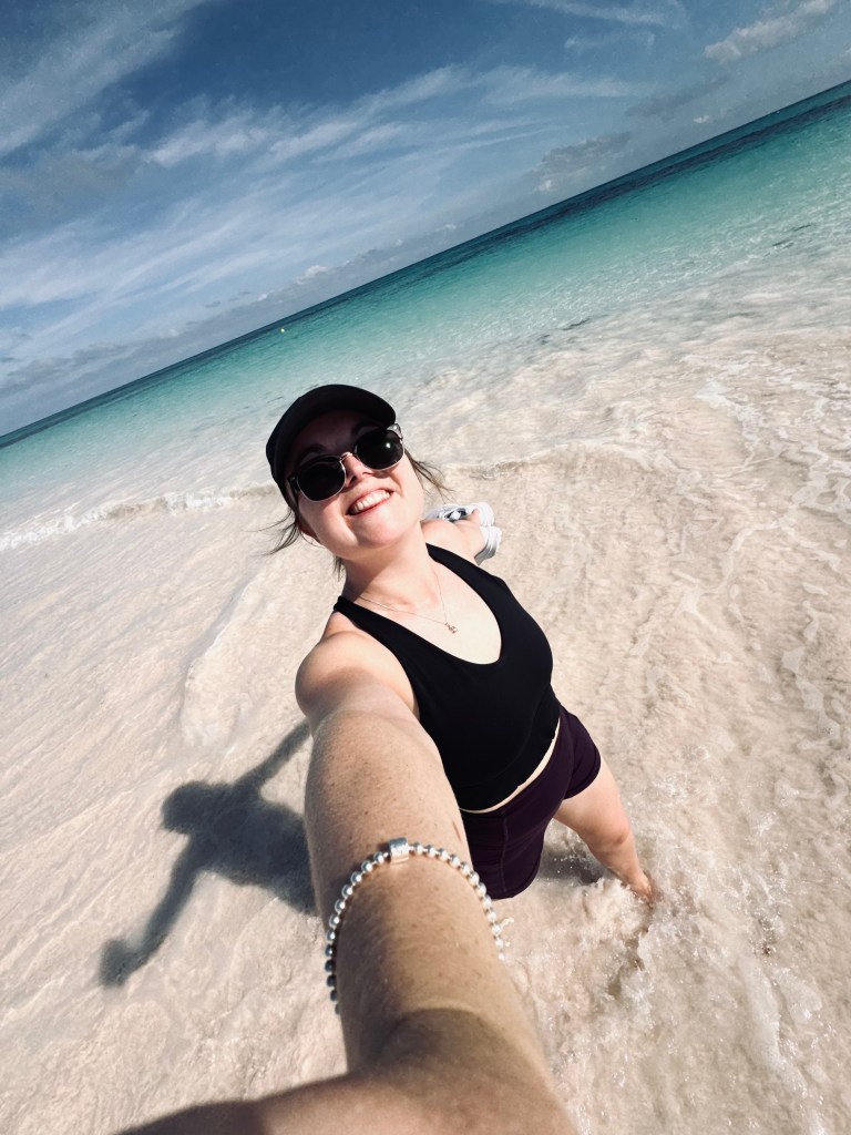Girl taking selfie while walking along the beach at Lookout Cay at Lighthouse Point on a Disney Cruise in the Bahamas