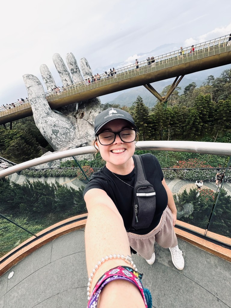 Girl taking selfie with Golden Bridge giant hands at Ba Na Hills, Vietnam