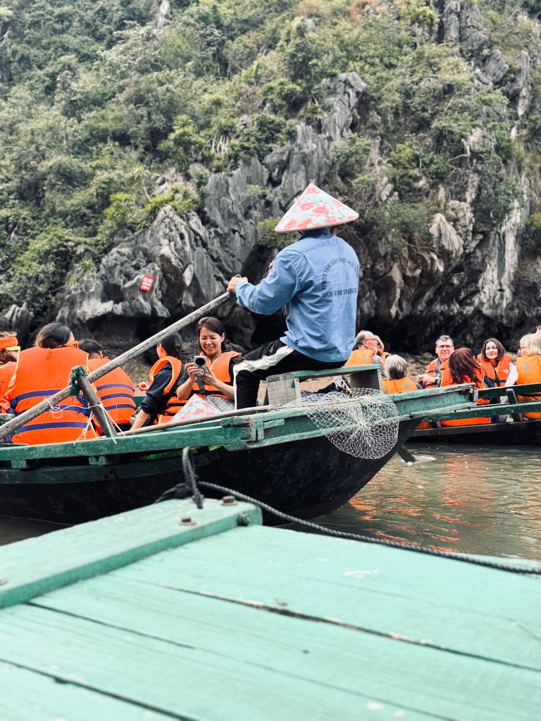Man in Vietnamese hat on a bamboo boat tour on Halong Bay cruise, Vietnam
