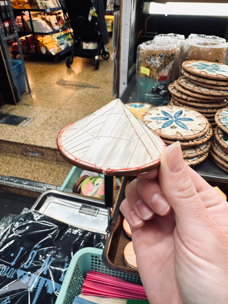 Hand holding souvenir of straw hat in Hanoi, Vietnam