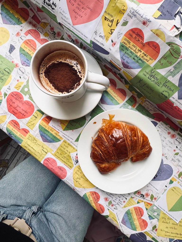 Croissant and Egg Coffee in a cafe covered in sticky notes at The Note Cafe in Hanoi, Vietnam