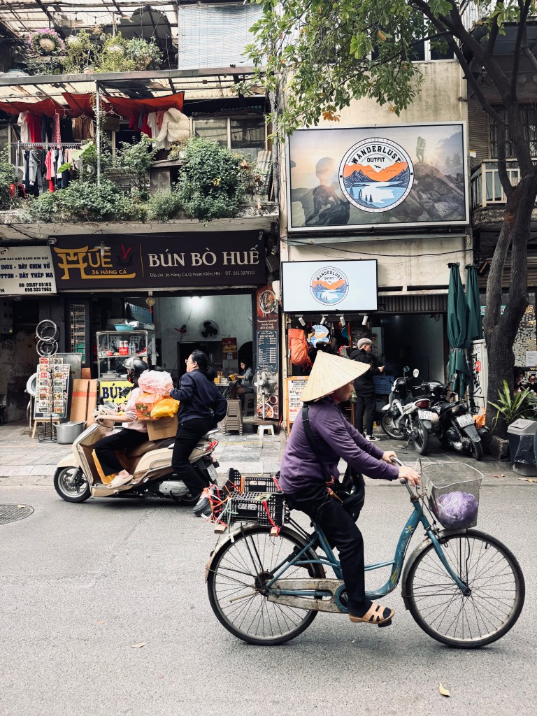 Busy streets in Old Quarter with local riding a bicycle with a straw hat in Hanoi, Vietnam