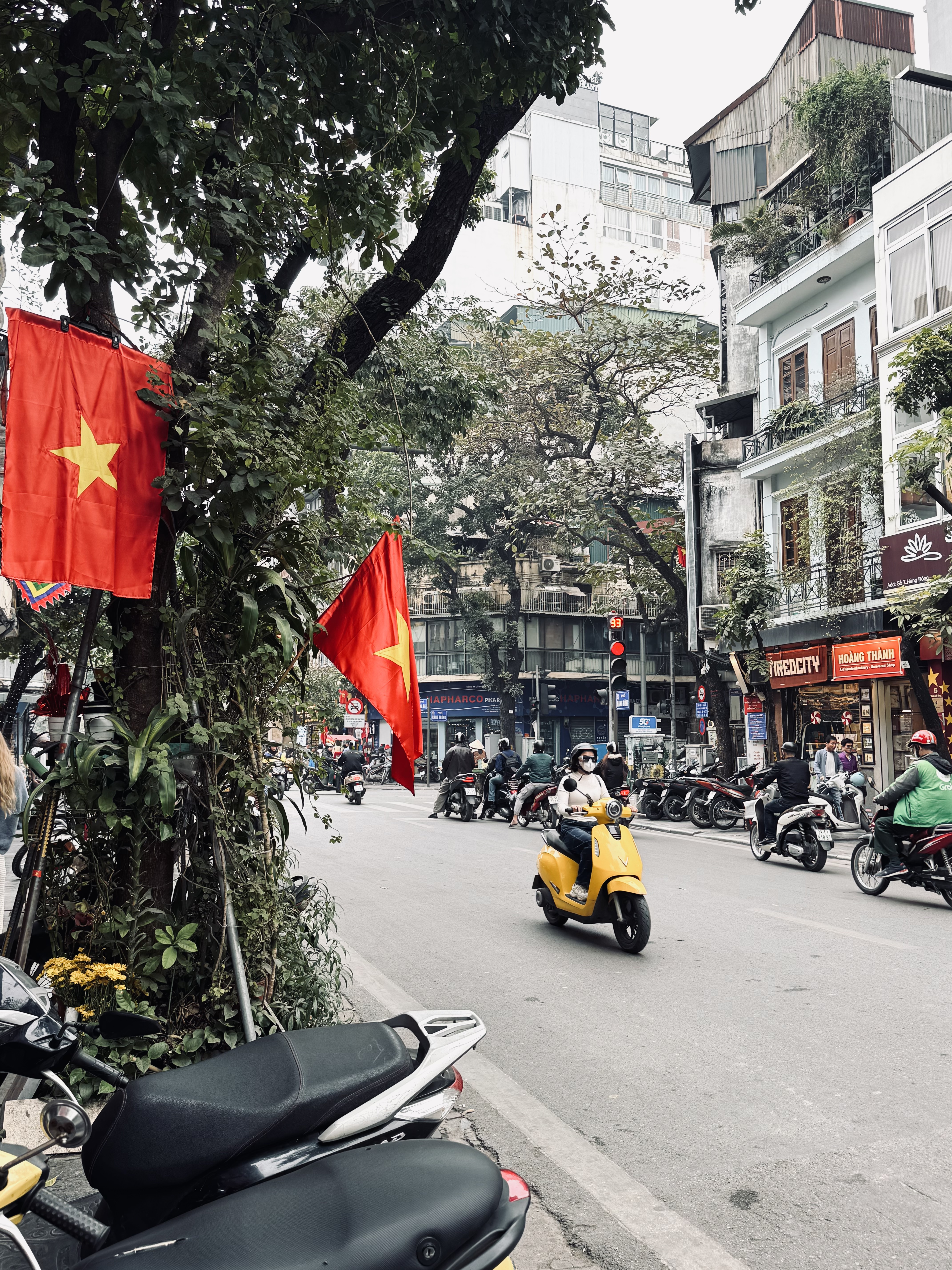 Streets of Old Quarter with mopeds and Vietnamese flags in Hanoi, Vietnam