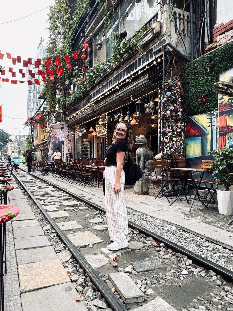 Girl smiling in front of cafes on Train Street in Hanoi, Vietnam